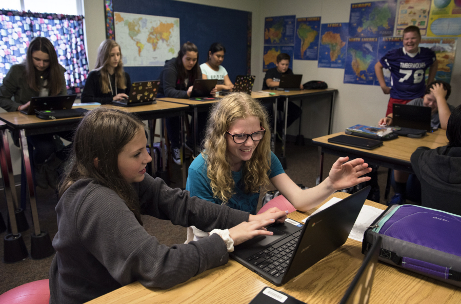 Frontier Middle School seventh-graders Sara Finnie, left, and Brynn Lantagne, right, use their Chromebooks to work on geography learning games during Kim Souchex’s humanities class.