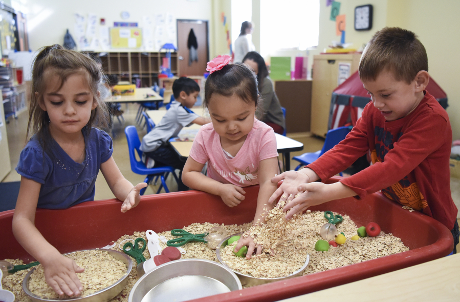 Aaralynn Marua, 4, from left, Alahoni Aguaro-Powell, 4, and Nathan Allan, 5, play with oatmeal in a blended preschool class at Hough Early Learning Center on Friday. About half the class are students with disabilities, while the other half are general education students.