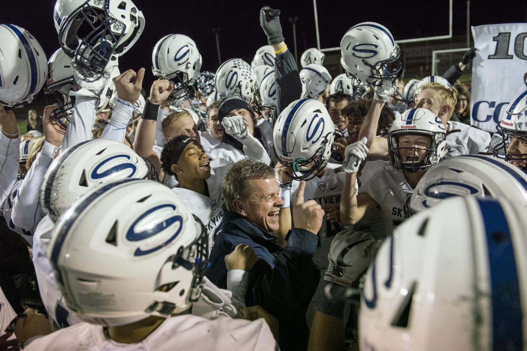 The Skyview football team surrounded coach Steve Kizer to celebrate his 100th win during Thursday night's game at Battle Ground District Stadium on Oct. 12, 2017.