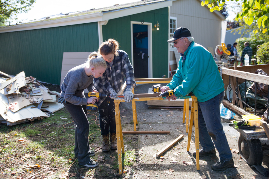 From left to right, Max Alexander and Gwen White, with the Young Democrats of Clark County, and Denny Kiggins, Clark Regional Wastewater District commissioner, construct a skirt for a Washougal mobile home during Evergreen Habitat for Humanity’s Elected Officials Build Day on Saturday. (Randy L.