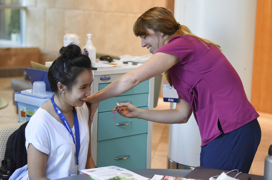 Nicole Nguyen, a volunteer at Legacy Salmon Creek Medical Center, left, receives a flu shot from registered nurse Lindsey Wreden on Friday. Wreden has for several weeks pushed a cart around the hospital, vaccinating employees and volunteers against the seasonal flu.