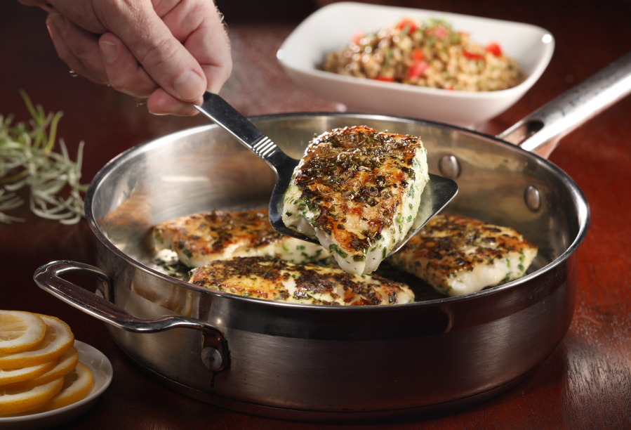 Halibut is coated with herbs before searing in a skillet, then the pan is transferred to the oven to finish cooking the fish without drying it out.