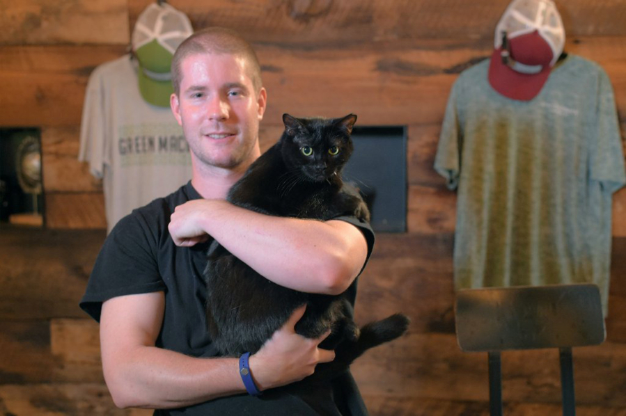 Diamondback Brewing Company co-founder Tom Foster holds Inky, a cat the brewery received from the BARCS “Working Cats” program.
