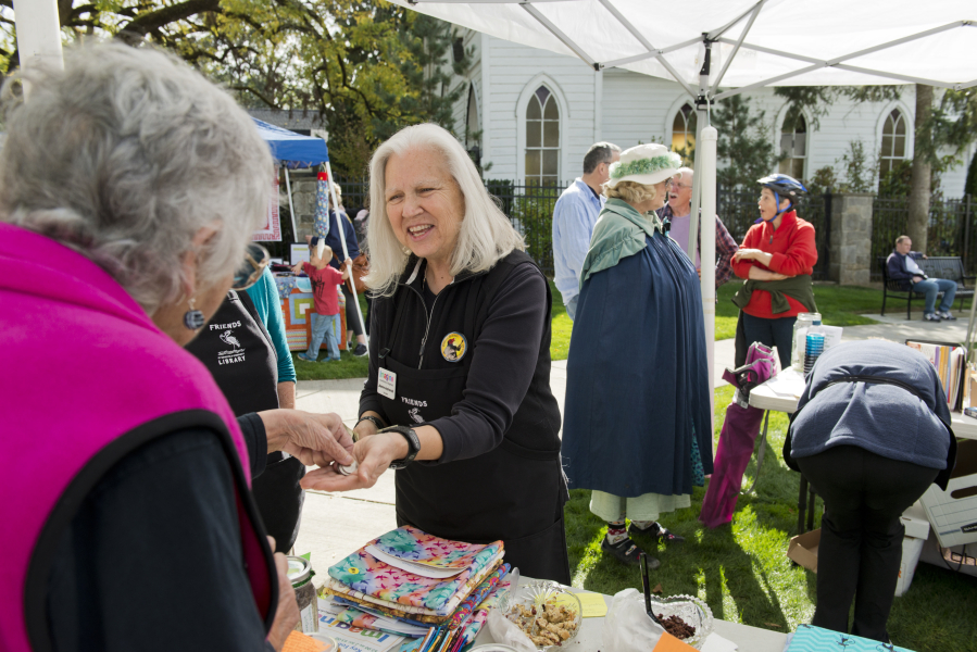 Lois Chapman, left, hands money to Jeanne Androvich, president of Friends of Ridgefield Community Library, after buying a book at a fund-raising event on Oct. 7.
