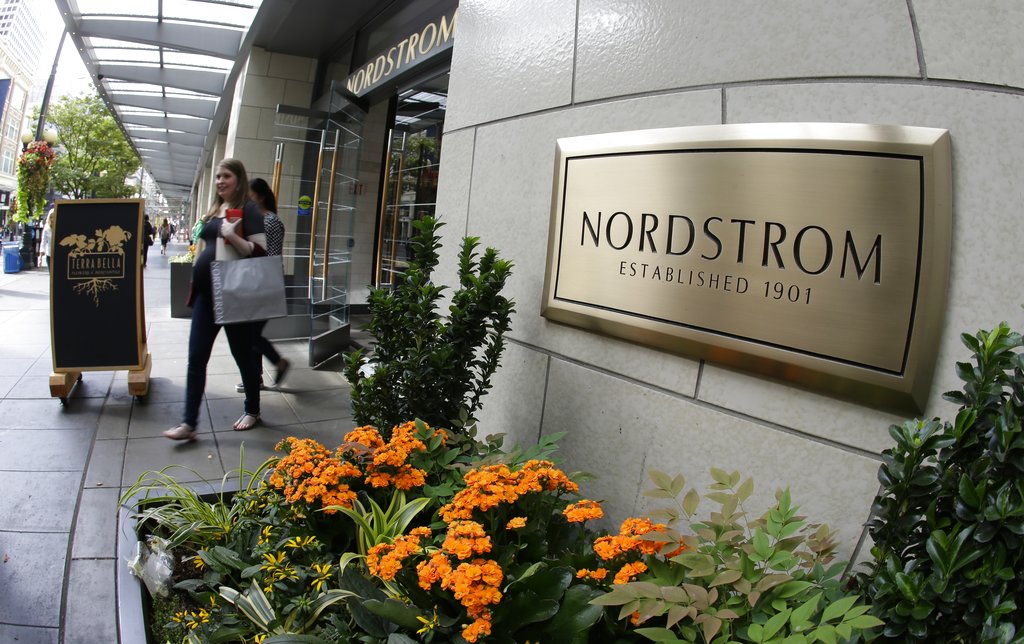 In this Wednesday, Sept. 13, 2017, photo, shoppers come and go from Nordstrom's flagship store in downtown Seattle. Nordstrom says it’s temporarily halting an exploration into taking the company private. The retailer said that a group that includes several members of the Nordstrom family plans to resume looking into a possible deal after the holiday season ends. (AP Photo/Ted S.