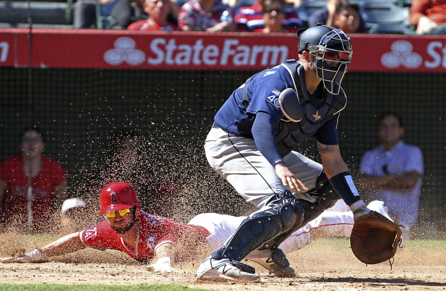 Seattle Mariners catcher Mike Marjama, right, waits for the throw as Los Angeles Angels’ Shane Robinson scores on Sunday.