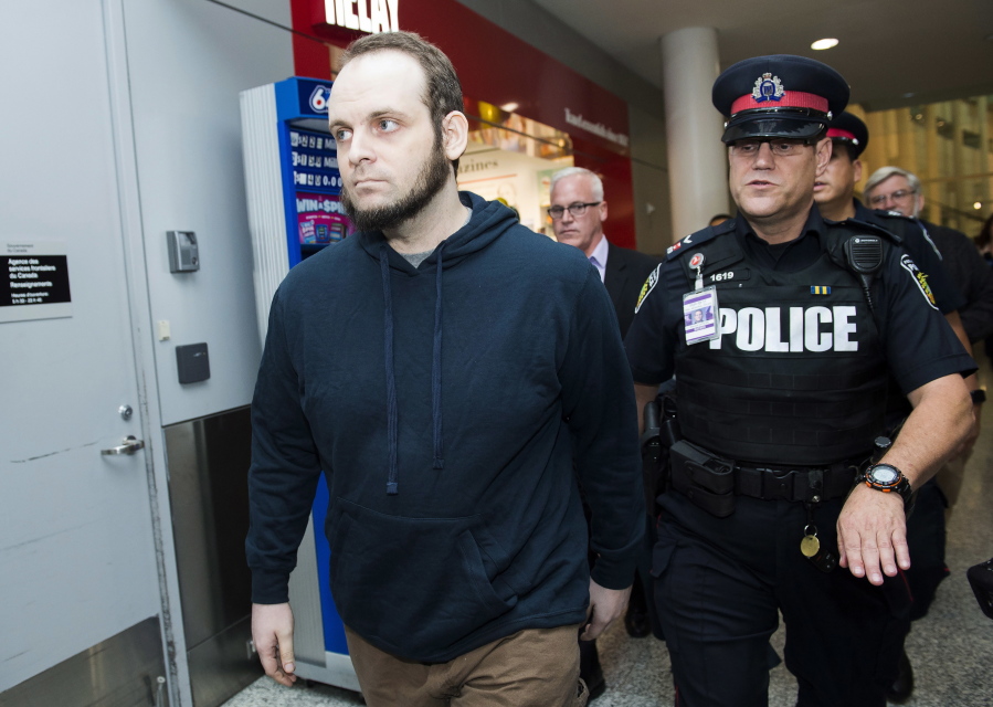 Joshua Boyle, left, gets a police escort after speaking to the media after arriving at the airport in Toronto on Friday, Oct. 13, 2017. Boyle, his wife Caitlin Coleman, and their three children landed in Canada after they were kidnapped in Afghanistan while on a backpacking trip and held hostage for five years by the Taliban-linked Haqqani network.