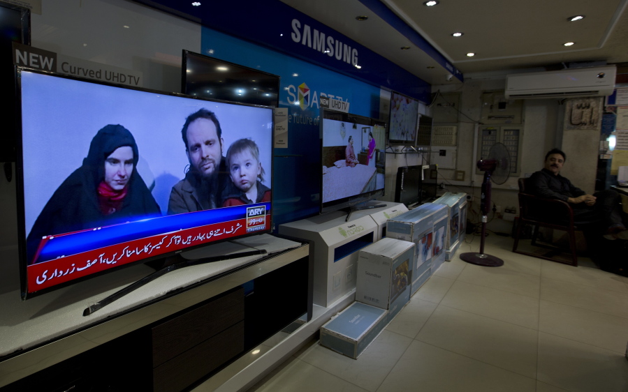 A Pakistani channel broadcasts a report about western couple, seen at a local electronic shop in Islamabad, Pakistan, Thursday. An American woman, her Canadian husband and their three young children have been released after years of being held captive by a network with ties to the Taliban, U.S. and Pakistani officials said Thursday. (AP Photo/B.K.