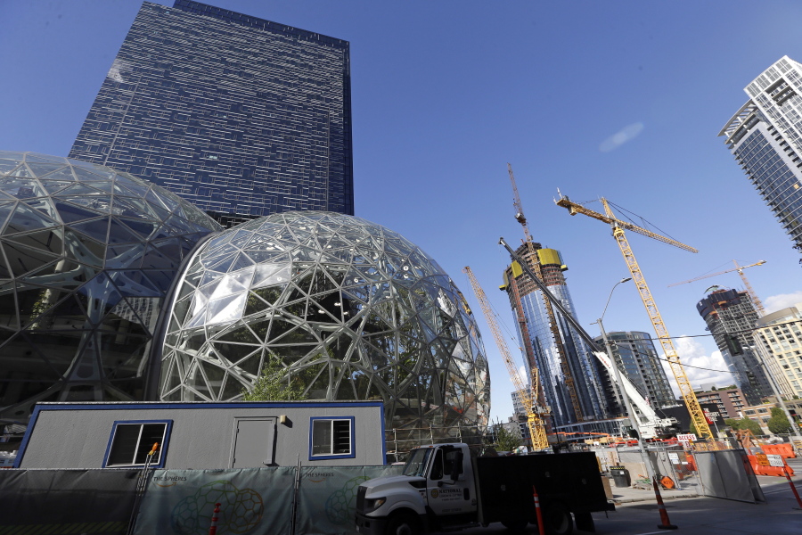 In this Wednesday, Oct. 11, 2017, photo, large spheres take shape in front of an existing Amazon building, behind, as new construction continues across the street in Seattle. Memo to the many places vying for Amazon’s second headquarters: It ain’t all food trucks and free bananas. For years now, much of downtown Seattle has been a maze of broken streets and caution-taped sidewalks, with dozens of enormous cranes towering overhead as construction trucks rumble past pedestrians and bicyclists. And while Amazon is far from solely to blame for these issues, and many say the benefits clearly outweigh the drawbacks, life has been disrupted.