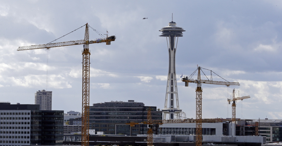Construction cranes in the South Lake Union neighborhood stand in view of the Space Needle on Wednesday in Seattle. The city is grappling with skyrocketing rent and housing prices.
