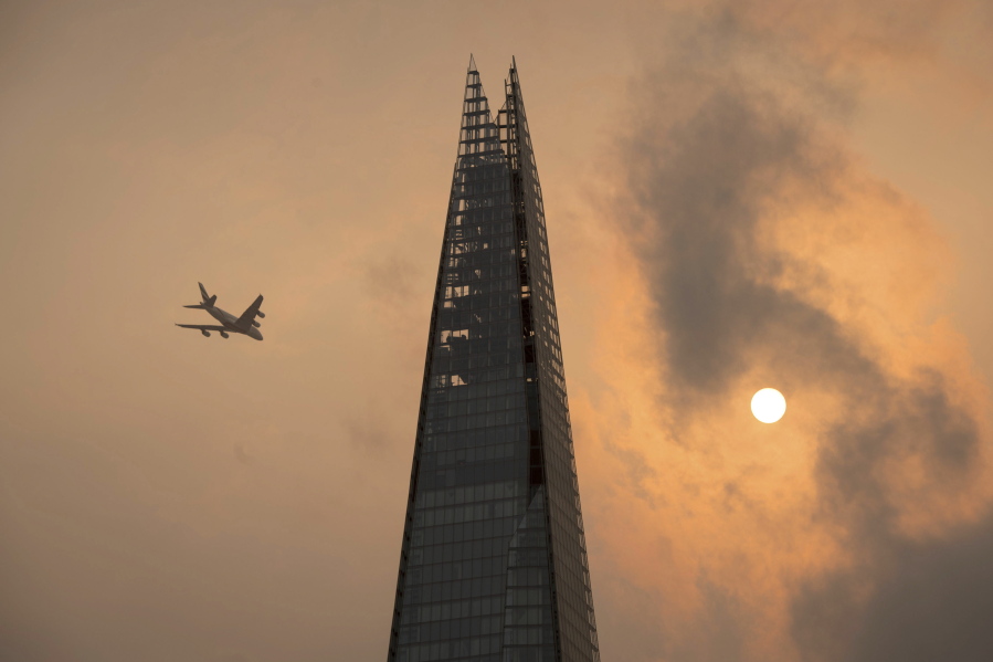 A plane flies past the Shard in central London, as the sky takes on an unusual orange colour caused by Hurricane Ophelia Monday Oct. 16, 2017. The unusual occurrence was due to the remnants of the hurricane dragging in tropical air and dust from the Sahara.