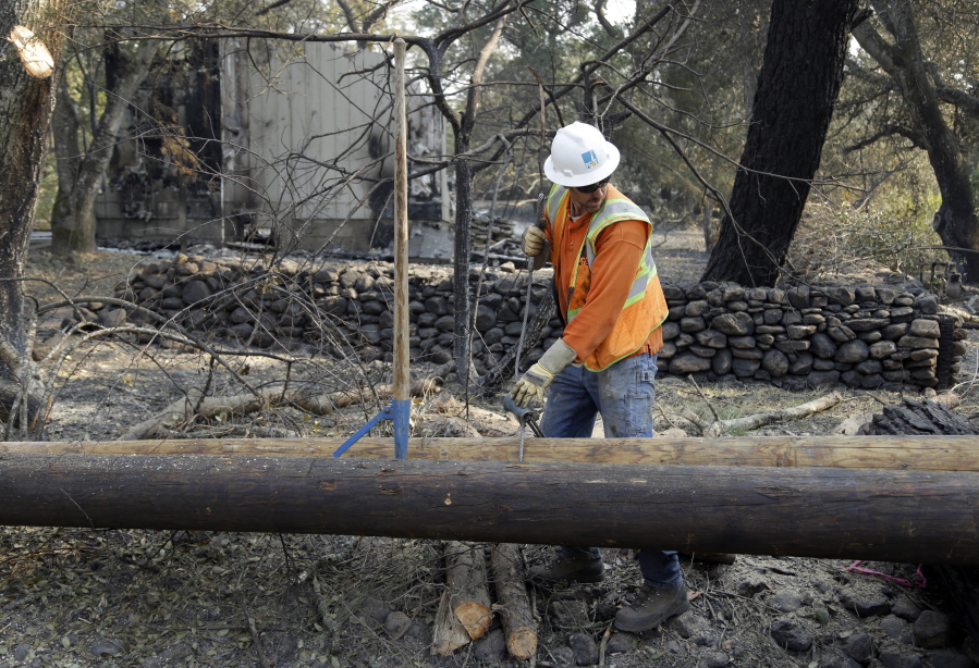 A Pacific Gas & Electric worker replaces power poles destroyed by wildfires on Wednesday in Glen Ellen, Calif. California fire officials have reported significant progress on containing wildfires that have ravaged parts of Northern California.