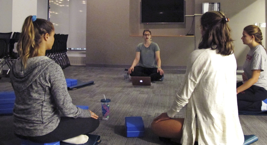 In this Sept. 12, 2017 photograph, students at the University of Vermont in Burlington, Vt., take a meditation class in a new Wellness Environment dormitory. The university has opened a dorm that goes beyond mere bans on drugs and alcohol to promote overall healthy lifestyles. Students meditate, practice yoga, eat well and make other healthy choices in the Wellness Environment.