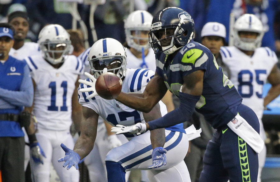 Seattle Seahawks cornerback Justin Coleman, right, intercepts a pass intended for Indianapolis Colts wide receiver Kamar Aiken, center, in the first half of an NFL football game, Sunday, Oct. 1, 2017, in Seattle. Coleman returned the pick for a touchdown.