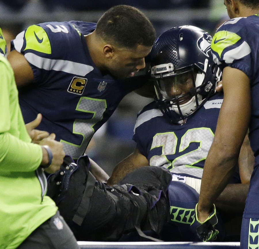 Seattle Seahawks quarterback Russell Wilson, left, comforts running back Chris Carson before Carson is taken away on a cart Sunday against the Indianapolis Colts.