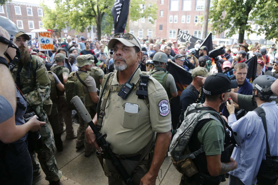 An armed militia member stands guard Aug. 12, at a white nationalist rally in Charlottesville, Va. The city of Charlottesville will join a lawsuit that seeks to prevent the heavily armed bands of white nationalists and militia groups that descended on the Virginia city for a violent summer rally from returning. The City Council held a special meeting Thursday, Oct. 12, where they voted to join the lawsuit.