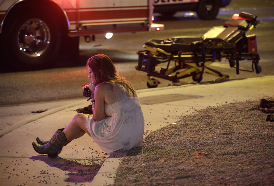 FILE - In this Monday, Oct. 2, 2017, file photo, a woman sits on a curb at the scene of a shooting outside of a music festival along the Las Vegas Strip. Months after Facebook and Google announced major efforts to curb the spread of false stories masquerading as news, it’s still cropping up, most recently in the wake of the Las Vegas mass shooting. Turns out it’s not so easy to re-engineer social media systems geared to maximize engagement over accuracy, especially when trolls and pranksters are scheming to evade those controls.
