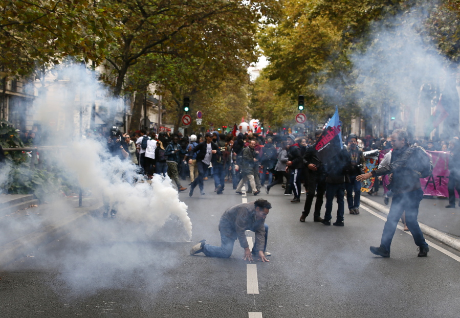 A demonstrators kneels though tear gas during a protest in Paris, Tuesday, Oct.10, 2017. Nine public sector unions called for nationwide industrial action to protest against President Emmanuel Macron’s economic policies, which they say would result in deteriorating work conditions.