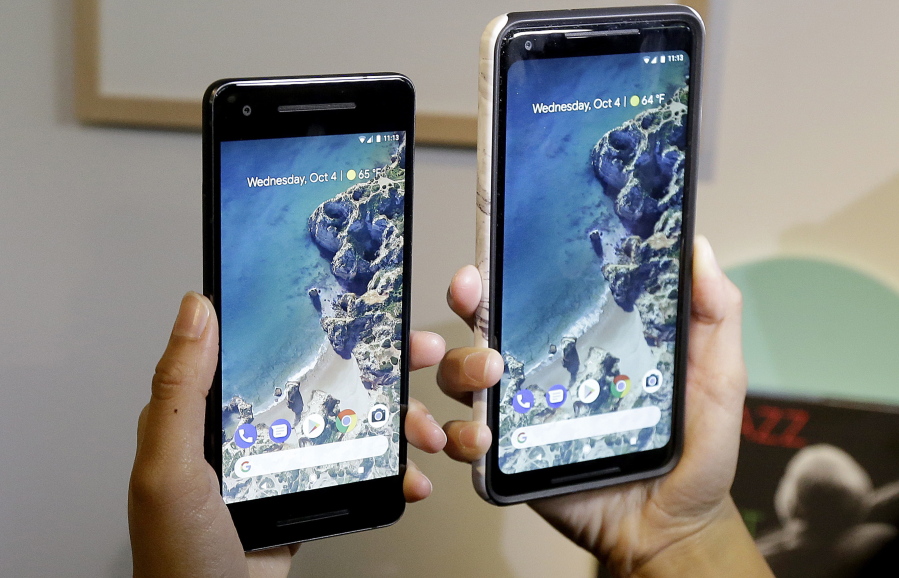 A woman holds up the Google Pixel 2 phone, left, next to the Pixel 2 XL phone at a Google event at the SFJAZZ Center in San Francisco, Wednesday, Oct. 4, 2017.