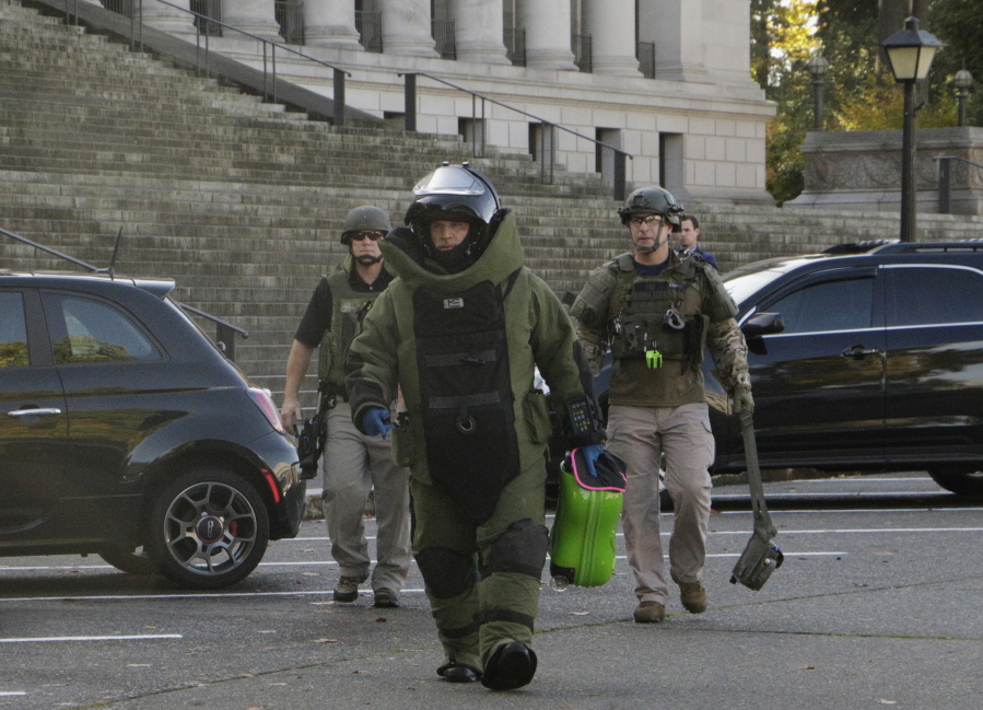 A member of the bomb squad carries a suitcase out of the Washington Capitol in Olympia on Monday.