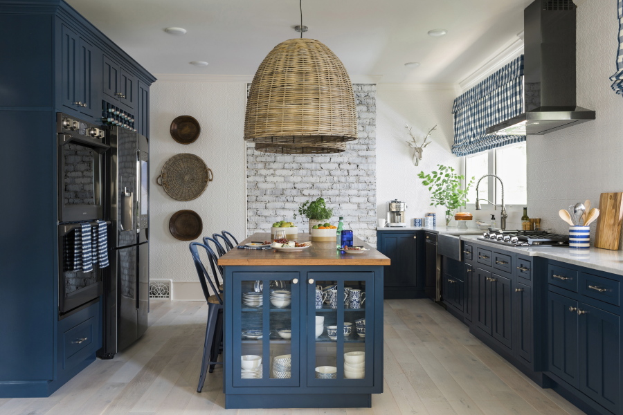 A kitchen designed by Brian Patrick Flynn features a L-shaped perimeter design with lower cabinets painted a rich shade of navy blue, a style choice that has become increasingly popular.