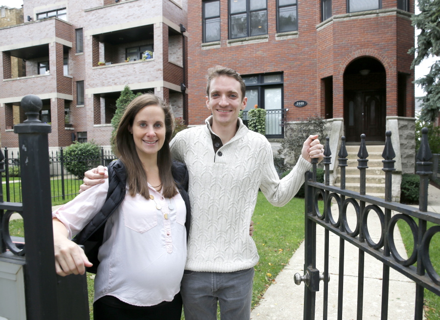 In this Sunday, Oct. 15, 2017, photo, Emily and Brian Townsend pose outside their home where they own the top floor unit in a three-flat building in Chicago.