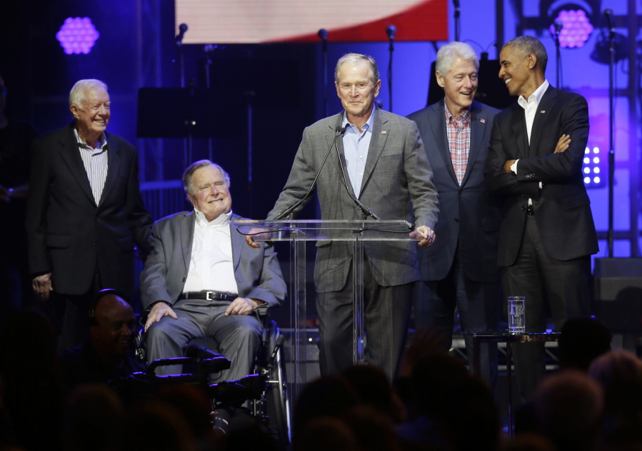 Former President George W. Bush, center, speaks as fellow former presidents, from right, Barack Obama, Bill Clinton, George H.W. Bush and Jimmy Carter look on during a hurricanes relief concert Saturday in College Station, Texas.