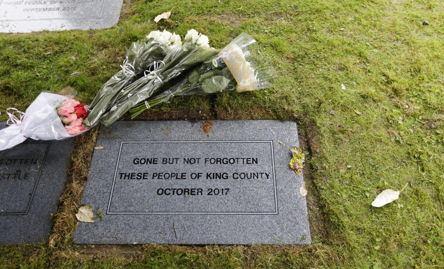 Flowers rest near a grave marker that reads “Gone but not forgotten, these people of King County October 2017” at Mount Olivet Cemetery in Renton.