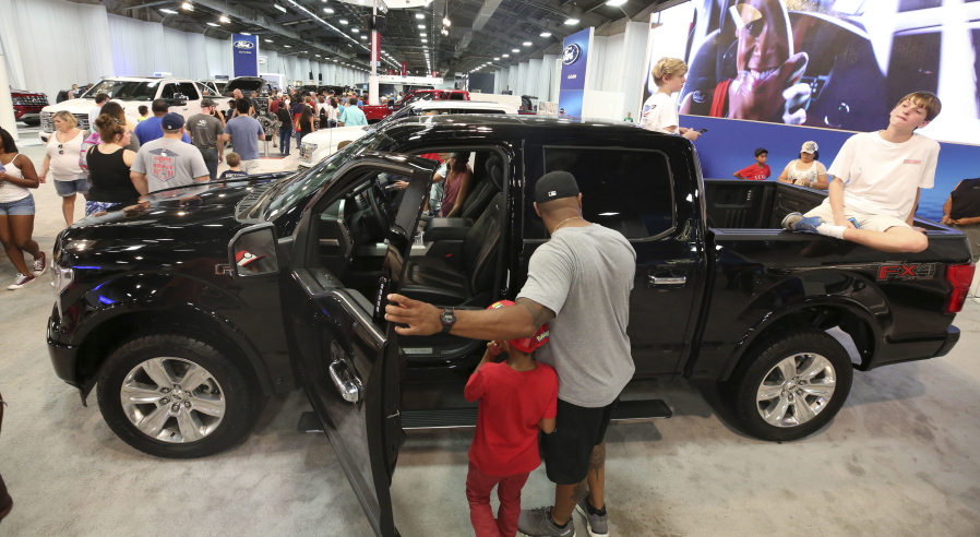 In this Monday, Oct. 9, 2017, photo, fairgoers look at pickup trucks on display at the State Fair of Texas in Dallas. America’s favorite luxury vehicle is a pickup truck. Buyers are increasingly outfitting their pickups with all the comforts of luxury cars, from heated and cooled seats to backup cameras to panoramic glass roofs.