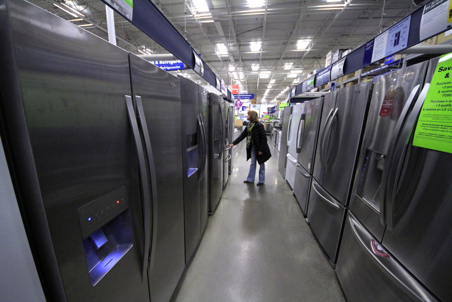 FILE - In this Thursday, Jan. 16, 2014, file photo, a woman walks through a display of refrigerators at a Lowe’s store in Cranberry Township, Pa. Buying a major appliance can be intimidating, but it doesn’t have to be hard. To find one that both you and your bank account are happy with, do your homework, visit a store and ask for a deal. And don’t buy an extra warranty without reading the fine print. (AP Photo/Gene J.