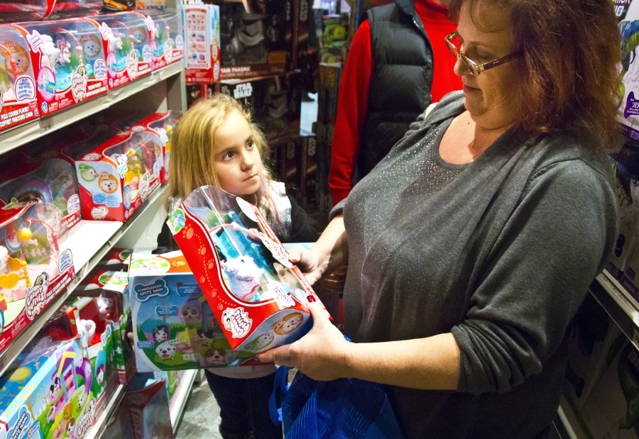Cinnamon Boffa, right, from Bensalem, Pa., checks out a Chubby Puppies toy for her daughter Serenity, left, at a Toys R Us, in New York.