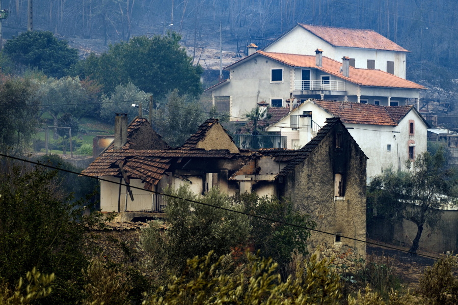 A burnt house stands next to others that were spared by a wildfire Monday near Penacova, Portugal.