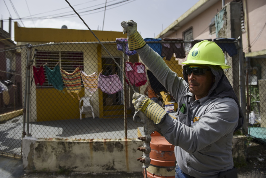 Ezequiel Rivera works with the Electric Energy Authority to restore distribution lines damaged by Hurricane Maria in the Cantera community of San Juan, Puerto Rico. The office of Gov. Ricardo Rossello said Thursday, Oct. 19 that about 20 percent of the island has service and he has pledged to get that to 95 percent by Dec. 31.