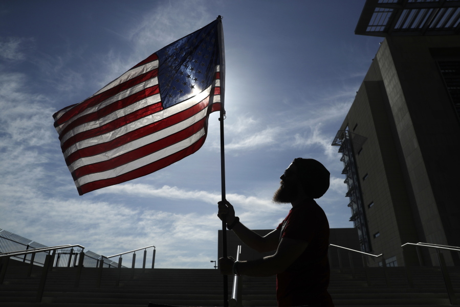 FILE - In this April 10, 2017 file photo, a protester holds up a flag outside of a federal courthouse in Las Vegas in support of defendants accused of wielding weapons against federal agents during a 2014 standoff involving cattleman and states’ rights advocate Cliven Bundy. Two Idaho men pleaded guilty Monday, Oct. 23, to lesser charges and will avoid a third trial in Las Vegas for having assault-style weapons during a confrontation with federal agents near Bundy’s ranch in 2014.