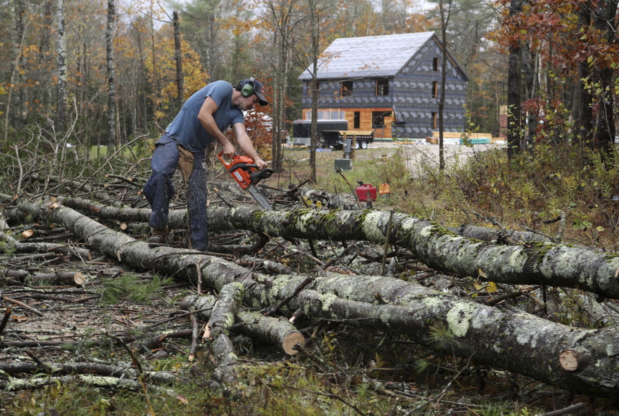 Pat Durham cuts pine tree that fell on Corey and Rachel Graham’s land in Freeport, Maine, on Monday. The storm toppled more than 20 pine trees on the lot but caused only minor damage to their property. (AP Photo/Robert F.