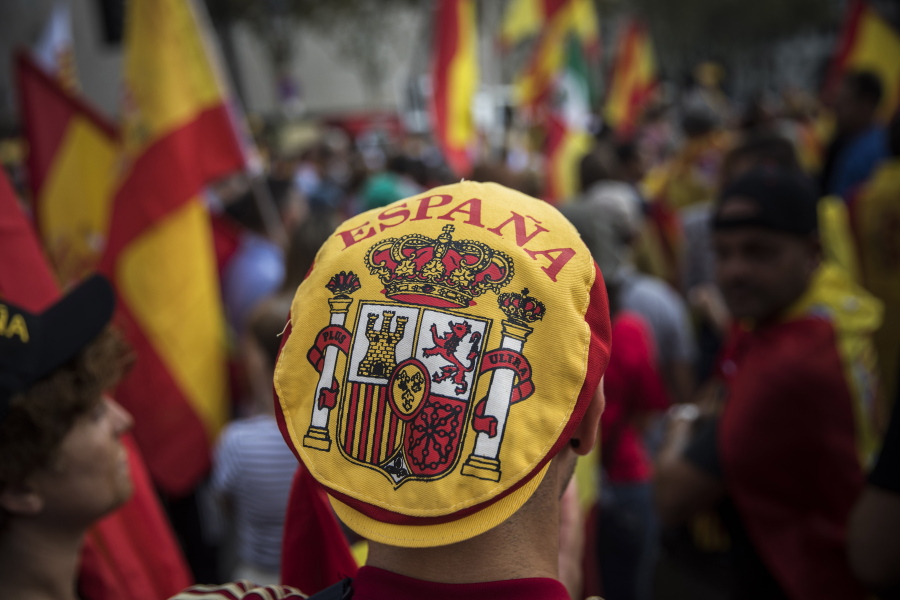 A man wears a hat with the coat of arms of the Spanish flag while people celebrate a holiday known as “Dia de la Hispanidad” or Spain’s National Day in Barcelona, Spain, Thursday. Spain’s celebrates its national day amid one of the country’s biggest crises ever as its powerful northeastern region of Catalonia threatens independence.