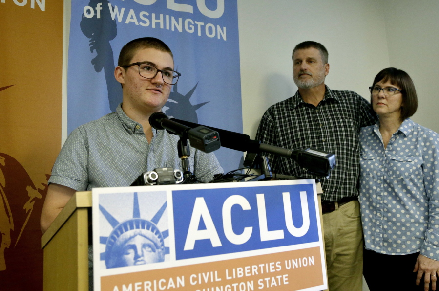 Paxton Enstad, left, speaks at a news conference about a lawsuit filed over refusal by an insurance plan to cover his gender-reassignment surgery as his parents, Cheryl and Mark Enstad, look on Thursday in Seattle.