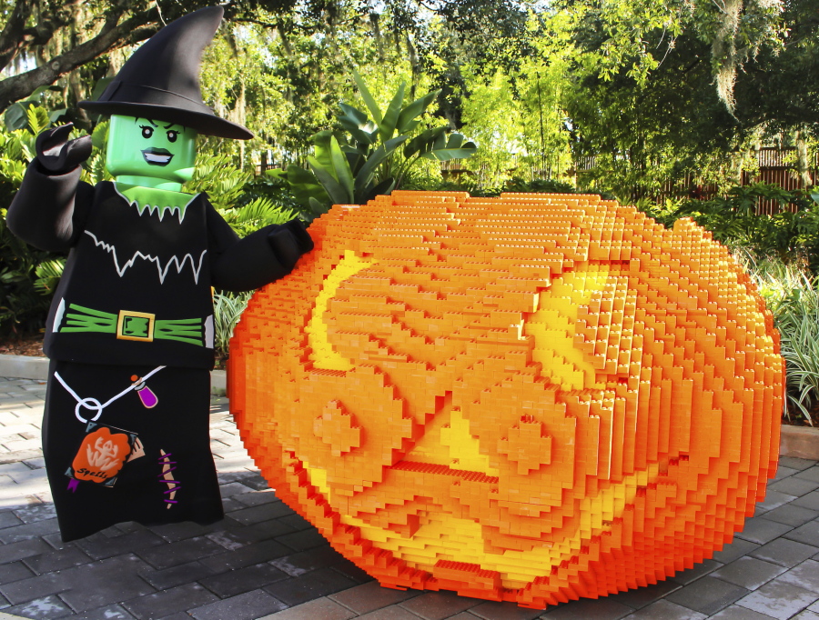 A giant pumpkin made from Legos at Legoland in Winter Haven, Fla., with a costumed greeter standing nearby.