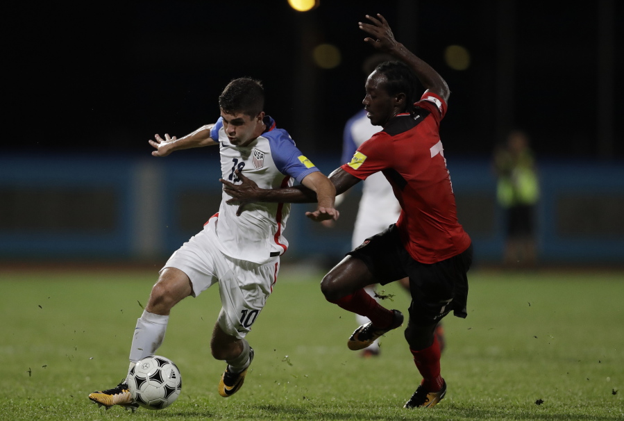 United States’ Christian Pulisic, left, fight for the ball with Trinidad and Tobago’s Nathan Lewis during a 2018 World Cup qualifying soccer match in Couva, Trinidad, Tuesday, Oct. 10, 2017.