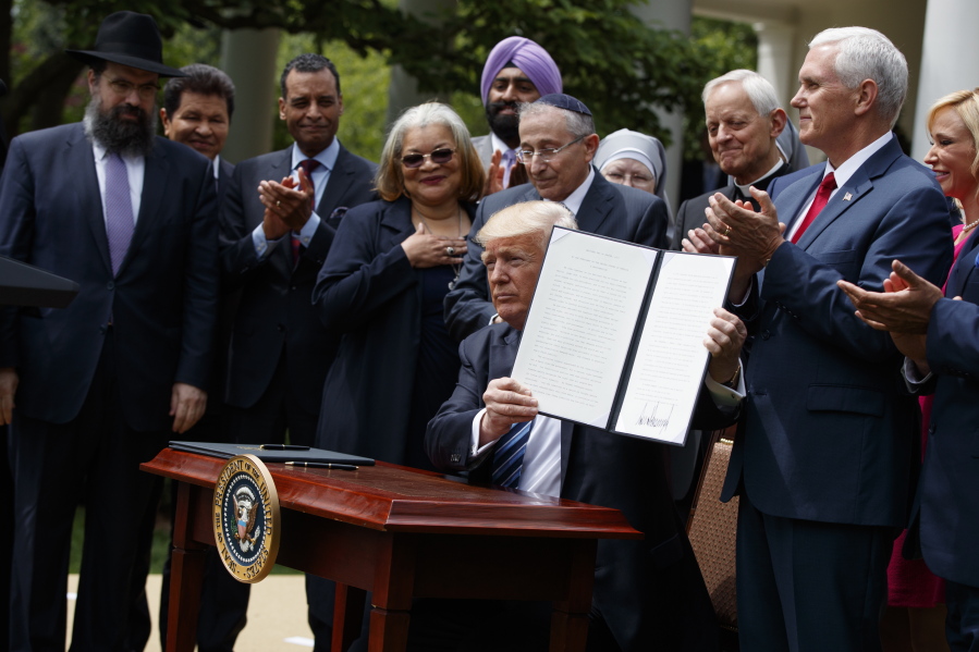In this May 4, 2017 file photo, President Donald Trump holds up a signed executive order aimed at easing an IRS rule limiting political activity for churches in the Rose Garden of the White House in Washington. In an order that undercuts federal protections for LGBT people, Attorney General Jeff Sessions issued a sweeping directive to agencies Friday to do as much as possible to accommodate those who claim their religious freedoms are being violated. Trump announced plans for the directive last May in a Rose Garden ceremony where he was surrounded by religious leaders. Since then, religious conservatives have anxiously awaited the Justice Department guidance.