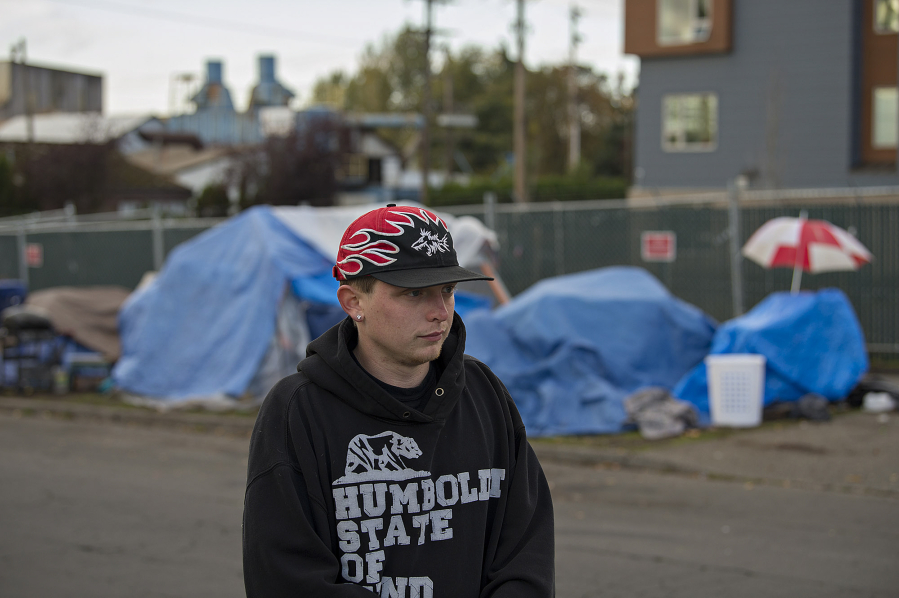 Homeless resident Michael McInerney stands Monday near tents as people camp along West 13th Street in Vancouver.
