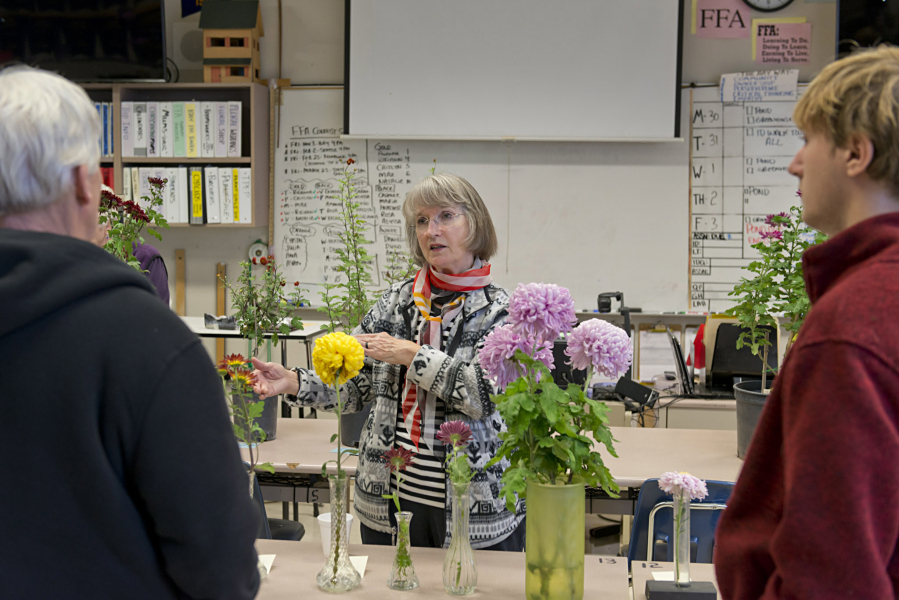 Elizabeth Adamson, Bill Wastradowski, left, and Micah Black talk shop about chrysanthemums Sunday at Hudson’s Bay High School, during the Vancouver Chrysanthemum Society’s annual flower show.