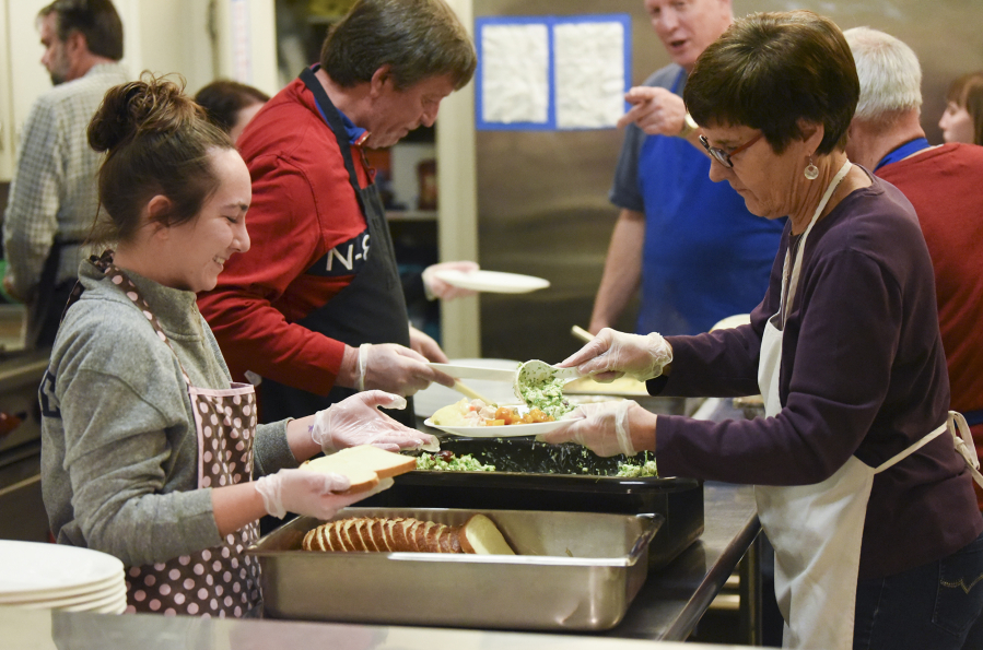 Volunteers Lauren Naughton, left, and Linda Meade, prepare dinner plates for the weekly Frassati supper served at the Proto-Cathedral of St. James the Greater in downtown Vancouver.