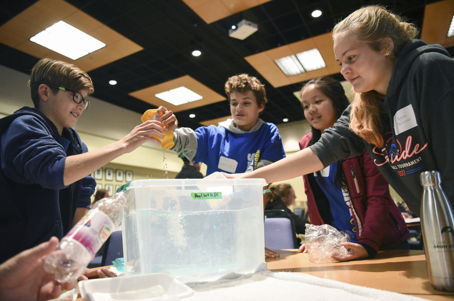 Our Lady of Lourdes Catholic School sixth-graders, from left, Andrew Dickson, Gabe DaSilva, Erin Chan and Alyssa Mancuso dunk plastic items into a tub of water to determine which ones float and which ones sink in a lesson about the ocean and reducing plastic consumption Thursday during the Clark County Green Schools summit at Clark College.