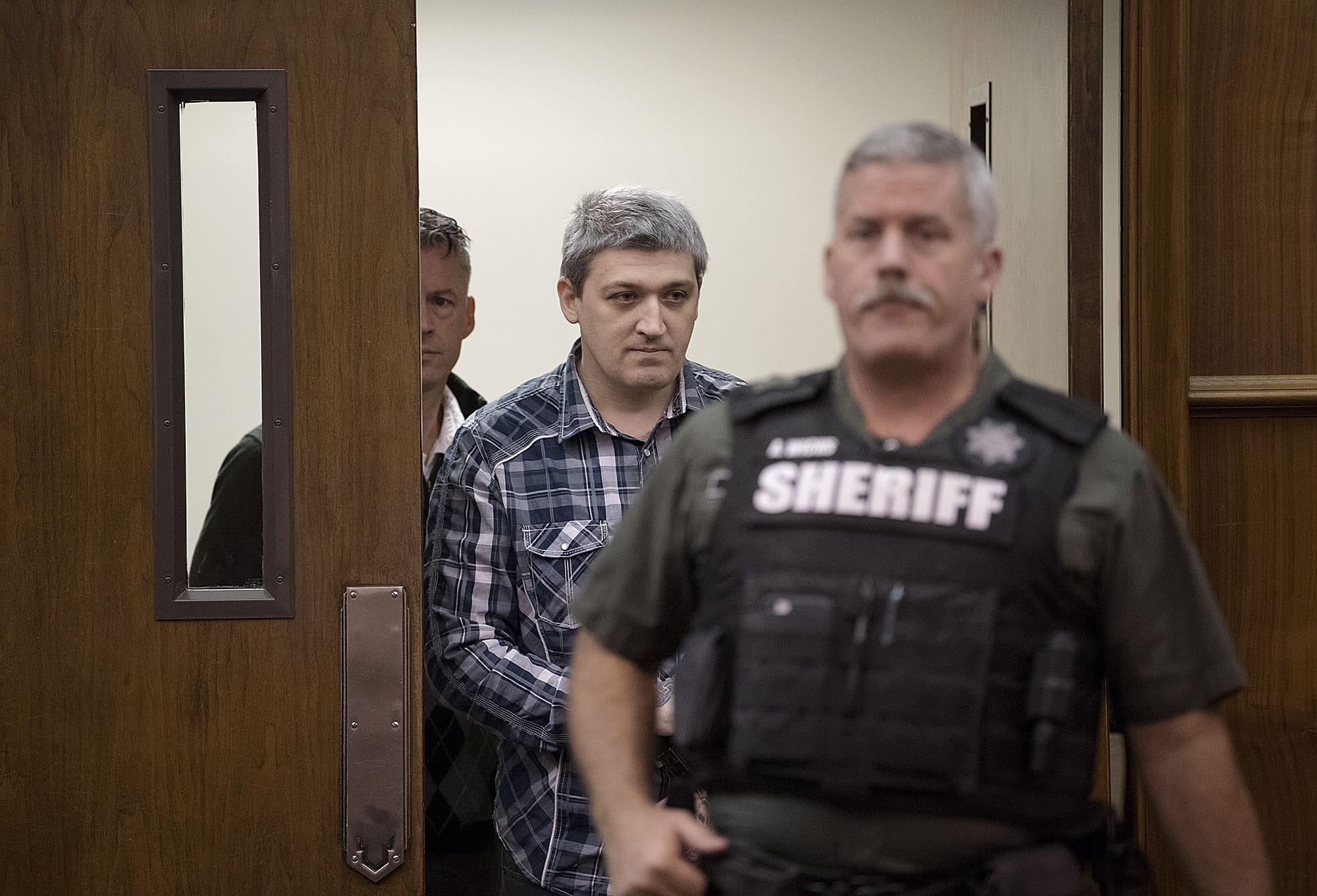 Brent Luyster, center, makes his way into the courtroom during his triple aggravated murder trial in Clark County Superior Court on Monday morning, Nov. 13, 2017.