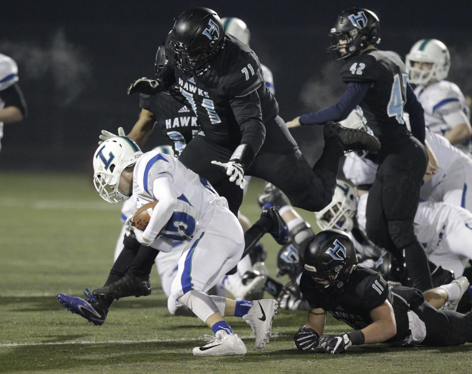 Hockinson nose guard Nathan Balderas (71) and linebacker Sawyer Racanelli (11) tackle Liberty wide receiver Reilly Larson in the 2A state football quarterfinals.
