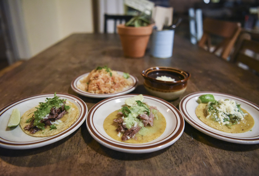 Rice and refried beans, top center, a lamb barbacoa taco, bottom left, carnitas caramelized pork taco and a rajas de pablano taco, the seasonal vegetable option, at Little Conejo in Vancouver.