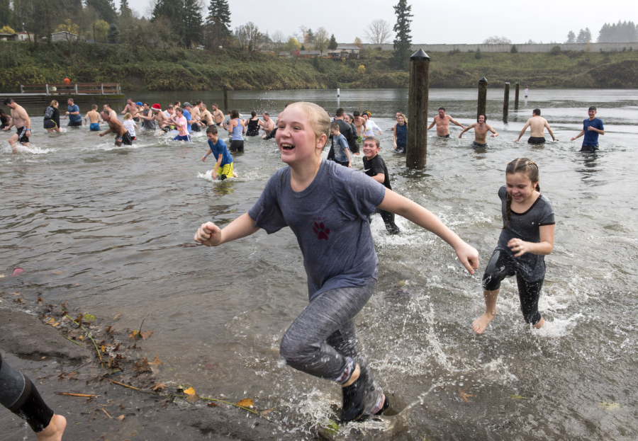 Ellie Vanschoiack, 12, of Vancouver, runs out of Klineline Pond after taking in a dip Thursday during the Polar Plunge at the Clark County 16th Annual Turkey Trot. More than 1,200 participants walked or ran and more than 100 swam during the Thanksgiving event. Top: Chase Lund, left, and his dad, Eric, try to push each other into the cold water of Klineline Pond.