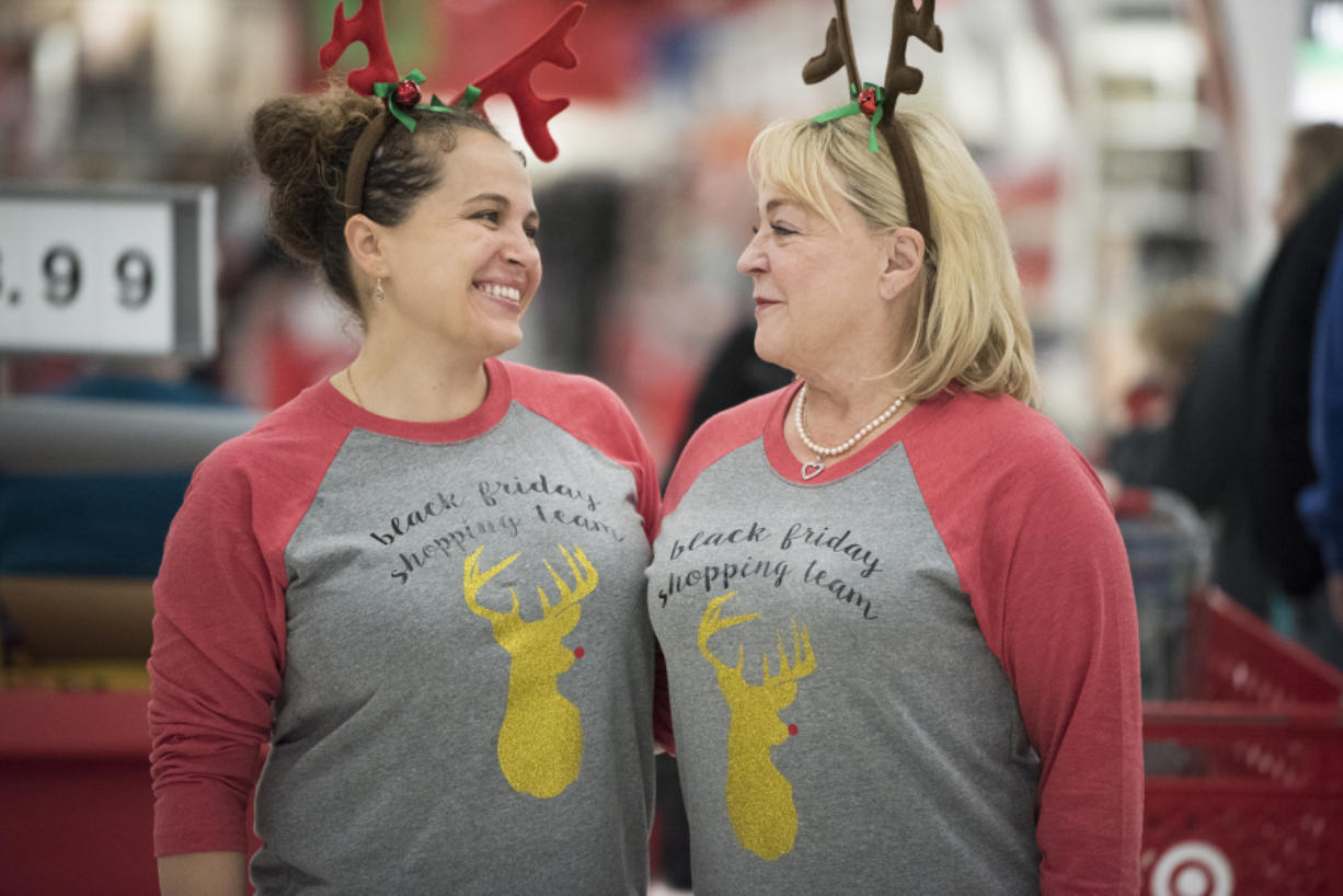 Friends Alicia Porter, left, and Beth Delmarter share a moment while shopping on Black Friday at Target on Southeast Mill Plain Boulevard. The pair were among seven extended family members who have made it a tradition to shop in Black Friday, wearing matching reindeer antlers and shirts.