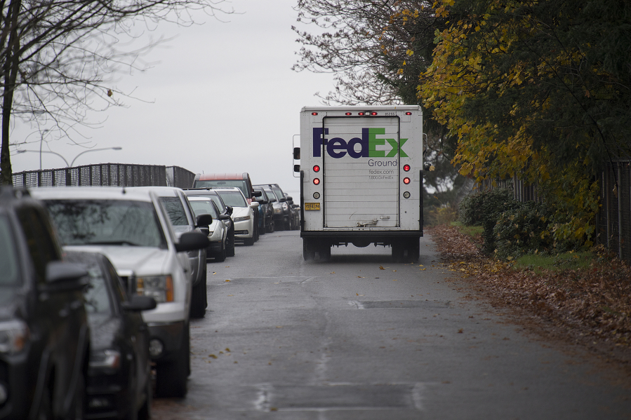 A FedEx truck passes a long line of parked cars Thursday along East Anderson Street, which has become increasingly congested from people parking along the road instead of paying for parking downtown. That congestion blocked truck access through the area until October, when the city of Vancouver restricted parking to one side.
